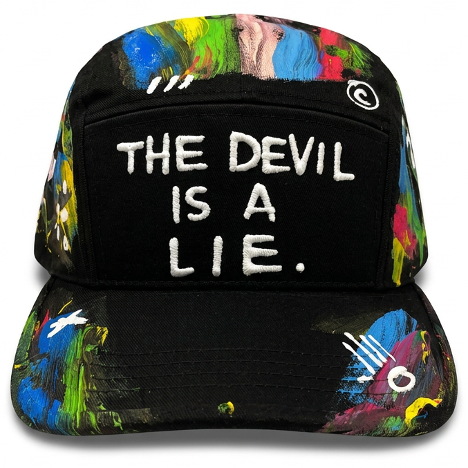 A black baseball cap with colorful abstract paint splatters on the brim and crown, featuring a front patch that reads 'THE DEVIL IS A LIE.' in white text.